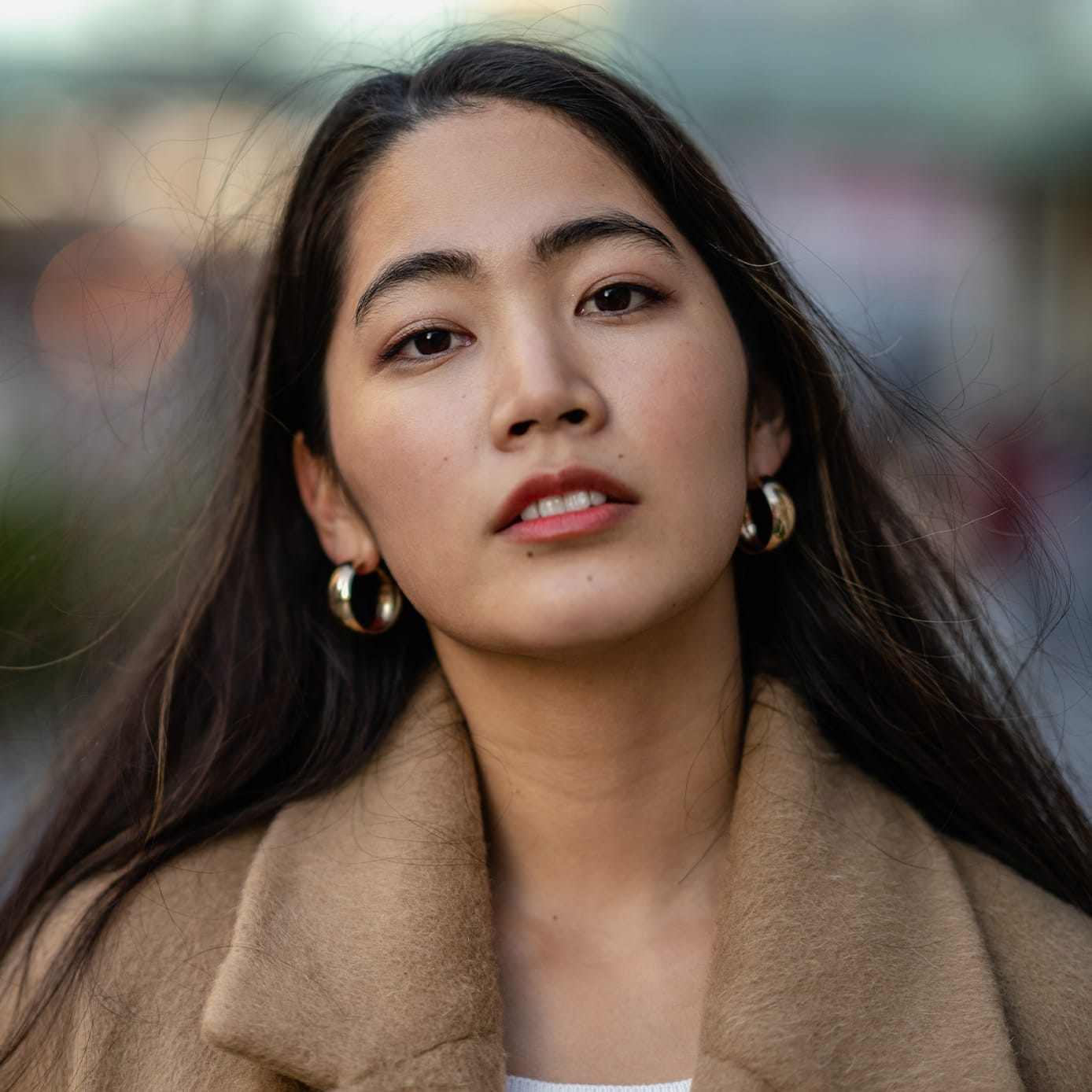 Woman in brown coat and gold earrings